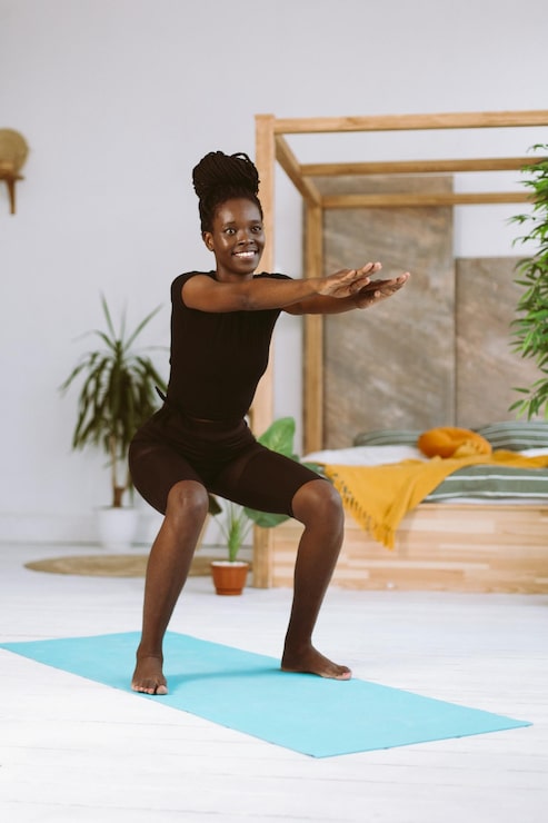 Woman performing a bodyweight squat | Holistic Menus
